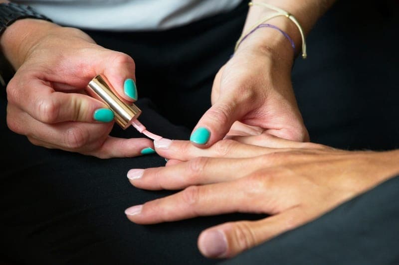 A manicurist applying polish to a client’s nails